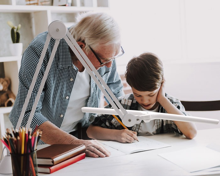 abuelo enseñando a su nieto a escribir con la lámpara lumi 